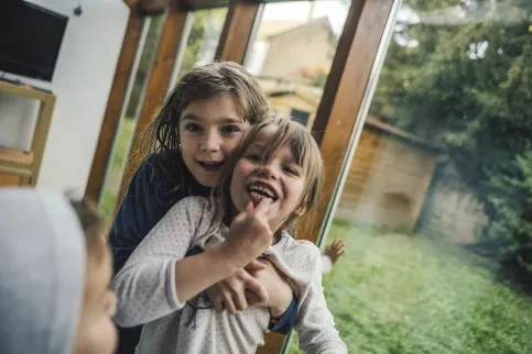 Lucie, au centre et en situation de handicap, reçoit un bisous de sa sœur à la Maison d'enfants Saint-François d'Assise