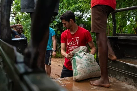 Un volontaire Apprentis d'Auteuil décharge un sac d'un 4x4