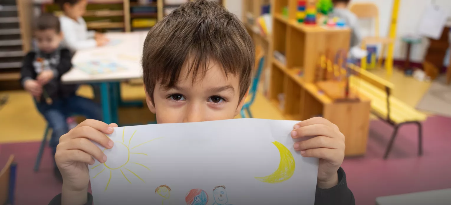 Enfant montrant son dessin à l'école