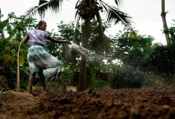 Une jeune tanzanienne arrose un jardin