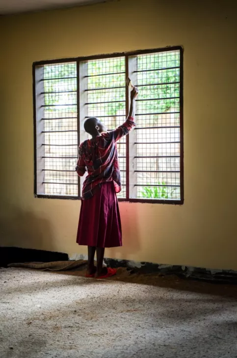 Une jeune femme peint une fenêtre dans une salle de classe