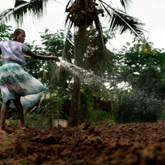 Une jeune tanzanienne arrose un jardin