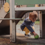 Un enfant ramasse une balle sous un toboggan